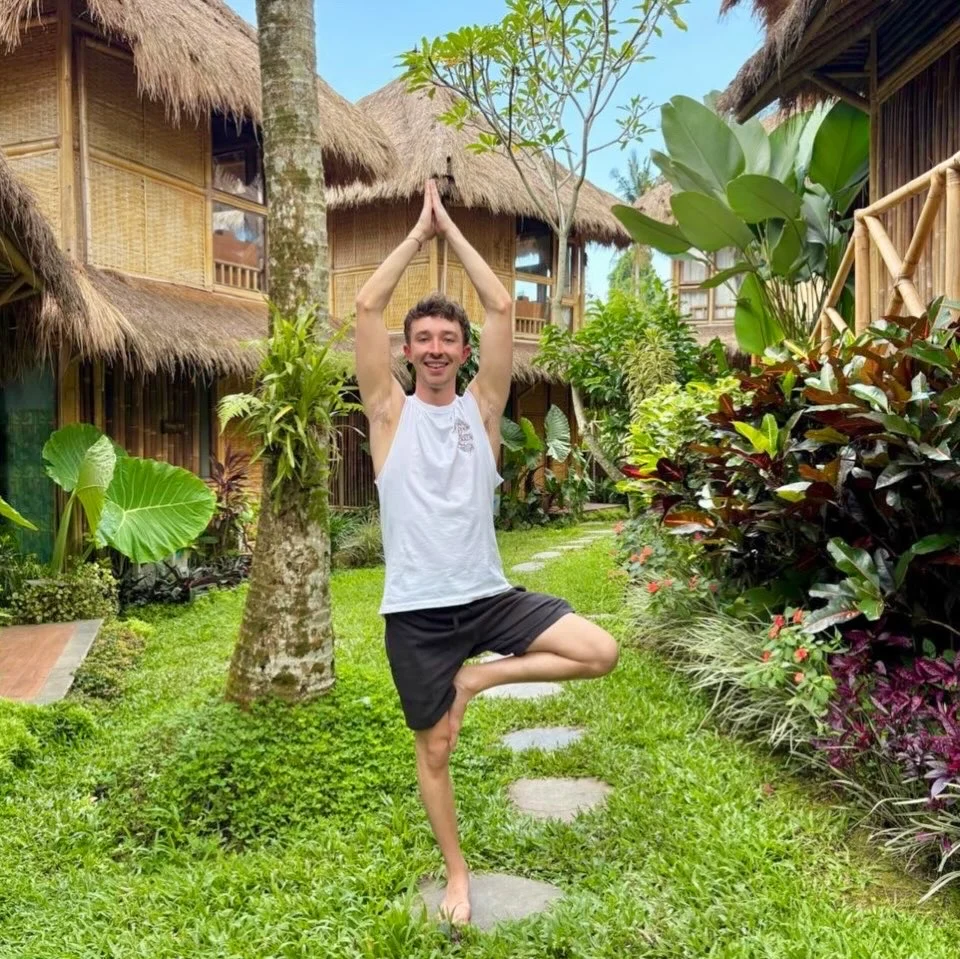 Max holding tree pose in a tropical garden